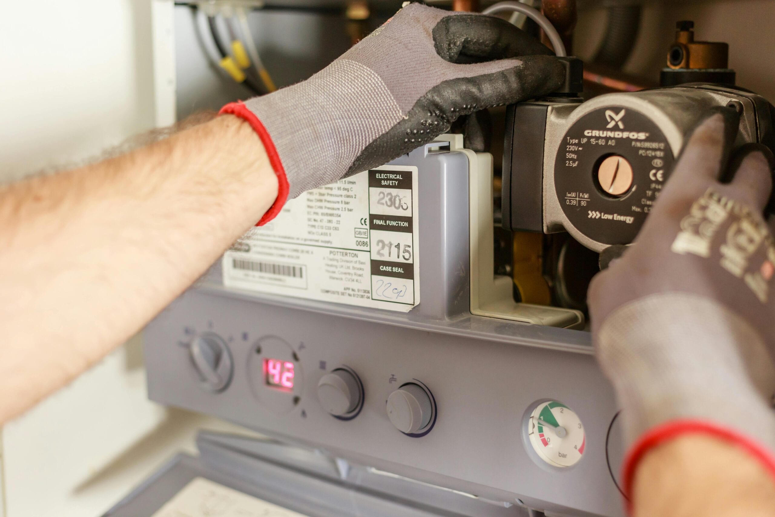 pexels-photo-7859953-7859953 Close-up of hands adjusting a boiler system with precise instrumentation, showing maintenance work.