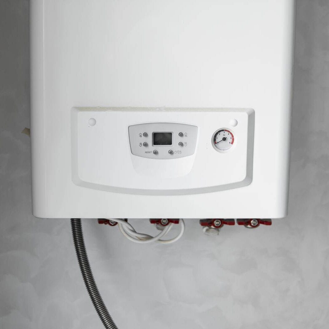 White modern home gas boiler mounted on a grey wall on a kitchen. Water heater. Water heating, ecology. White modern home gas boiler mounted on a grey wall on a kitchen. Water heater. Water heating, ecology