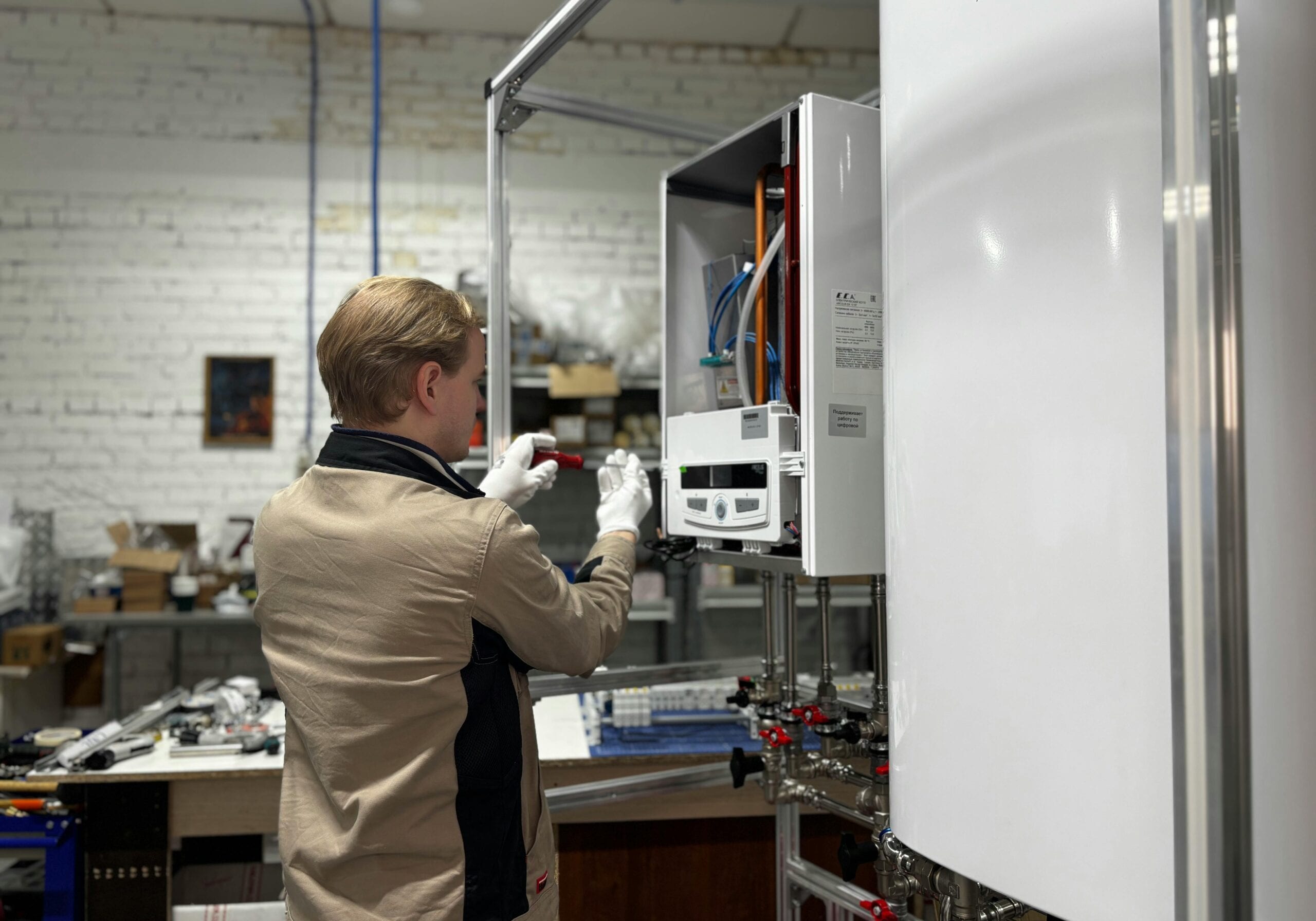 pexels-photo-34938442-34938442 Technician inspects and repairs a heating system in an industrial workshop setting.