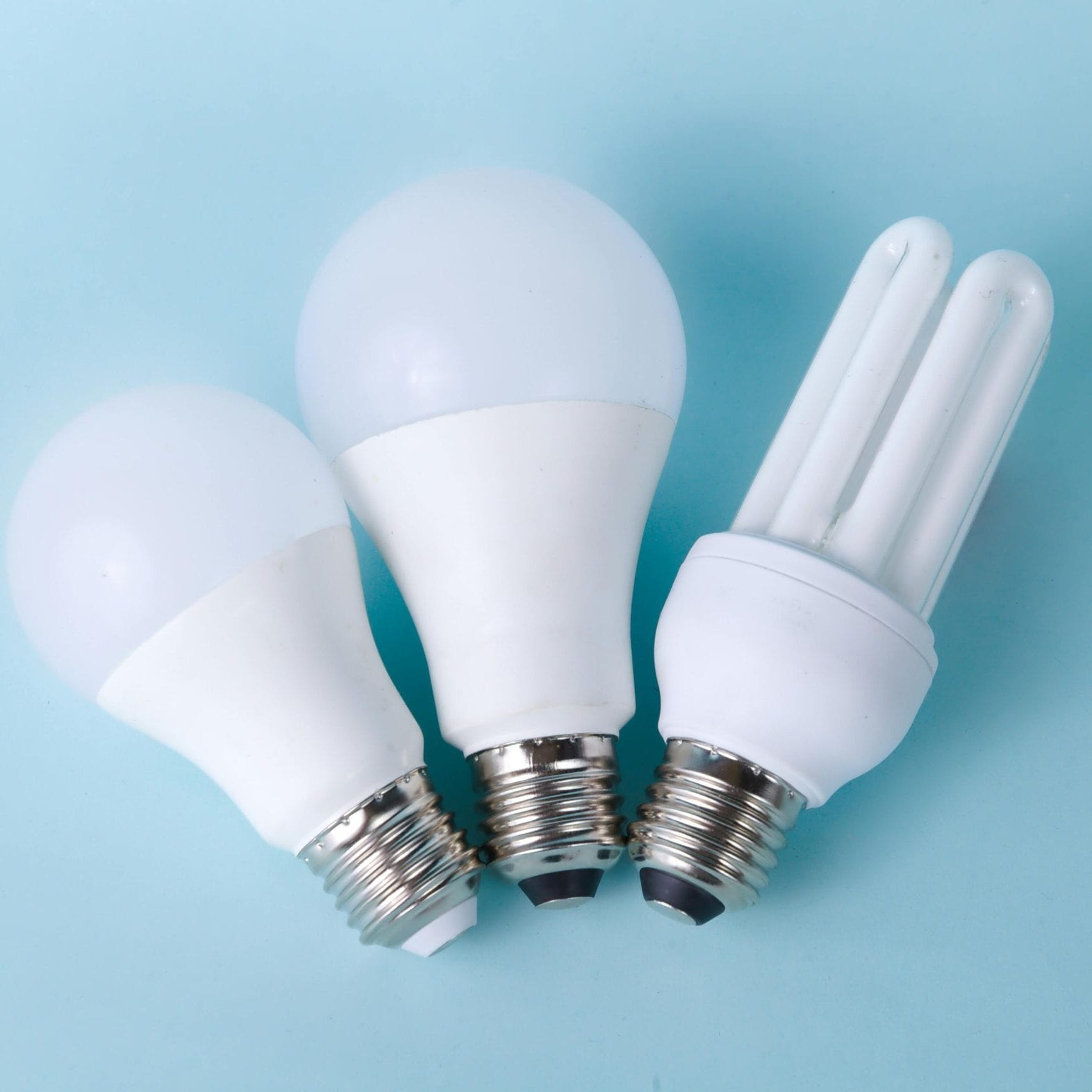 pexels-photo-3946152-3946152 Three assorted LED and CFL light bulbs against a light blue background.